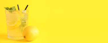 Sarı zemin üzerinde bir bardak taze limonata ve metin için yer var.
