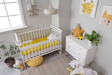 Bebek beşiği, oyuncakları ve tuvaleti olan aydınlık yatak odasının içinde.