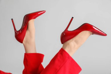 Gri arka planda kırmızı topuklu kadın bacakları