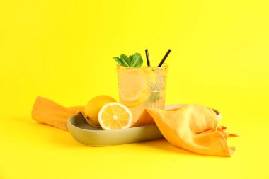 Sarı zemin üzerinde taze limonata olan tabak ve cam.