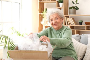 Kıdemli kadın evde paket açıyor.
