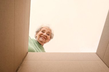 Paketi açık olan yaşlı kadın, içeriden bakıyor.