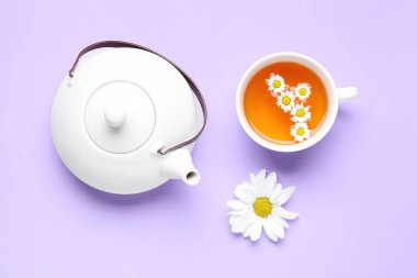 Bir fincan doğal papatya çayı ve leylak arkaplanda çiçekler.