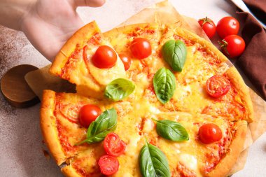 Bir kadın beyaz masada lezzetli bir pizza alıyor.