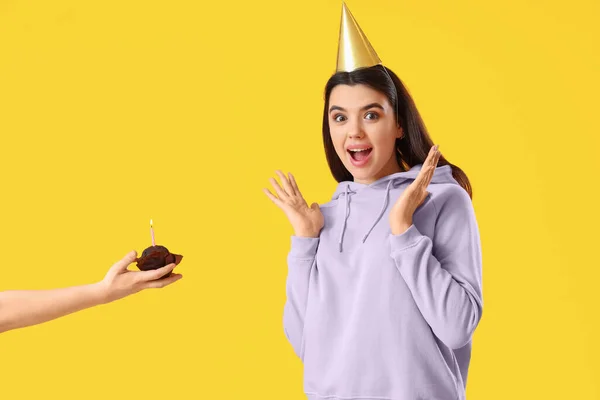 Überraschte Junge Frau Und Hand Mit Geburtstagstorte Auf Gelbem Hintergrund — Stockfoto