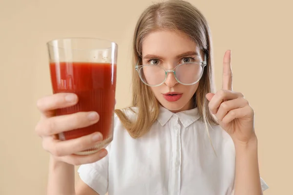 年轻女人用蔬菜汁指着米色背景的东西 — 图库照片
