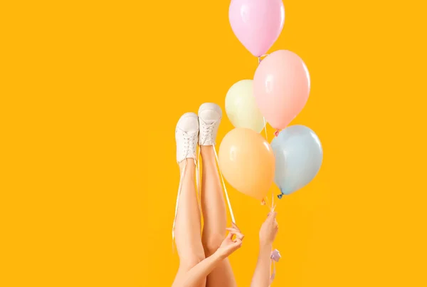 Jovem Amarrando Sapatos Atacadores Com Balões Fundo Amarelo — Fotografia de Stock