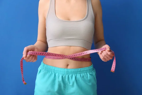 有蓝色背景的测量带的年轻女人 饮食概念 — 图库照片