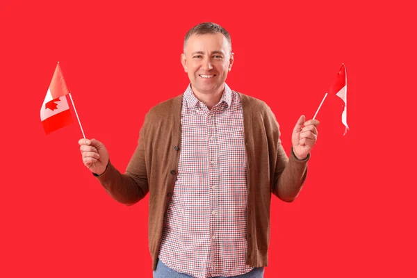 Reifer Mann Mit Kanadischen Flaggen Auf Rotem Hintergrund — Stockfoto