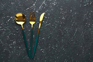 Koyu grunge arka planında yeşil saplı altın çatal bıçak takımı
