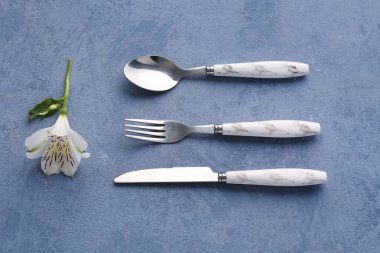 Mavi grunge arka planda gümüş çatal bıçak takımı ve alstroemeria