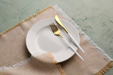 Altın çatallı tabak, bıçak ve mutfak peçetesi yeşil grunge arka planda