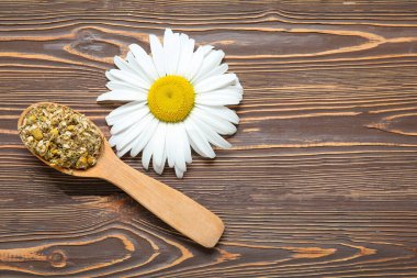 Kurumuş kaşık ve ahşap arka planda taze papatya çiçekleri.