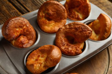 Ahşap arka planda lezzetli Yorkshire pudingi olan teneke fırın.