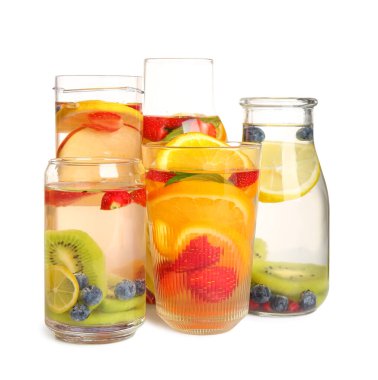 Beyaz arka planda farklı kesilmiş meyvelerle doldurulmuş bardaklar ve şişeler.