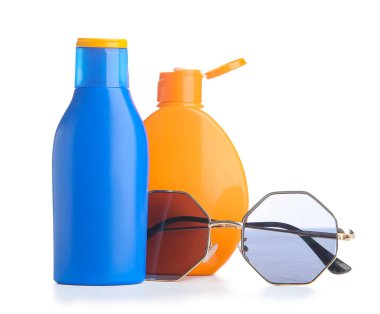 Beyaz arka planda güneş gözlüklü güneş kremi şişeleri