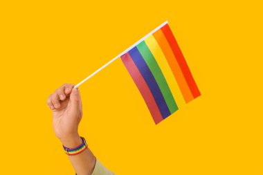 Sarı arka planda LGBT bayrağı olan genç adam.