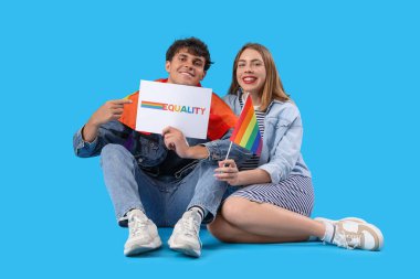 Kelime eşitliği ve mavi arka planda LGBT bayrakları ile kağıda işaret eden genç çift