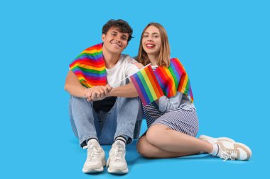 Mavi arka planda oturan LGBT bayraklı genç çift