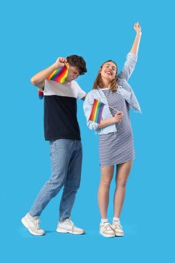 Mavi arka planda LGBT bayrakları olan mutlu genç çift