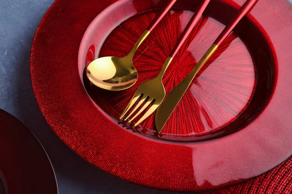stock image Golden cutlery with red plate and kitchen mat on blue grunge background