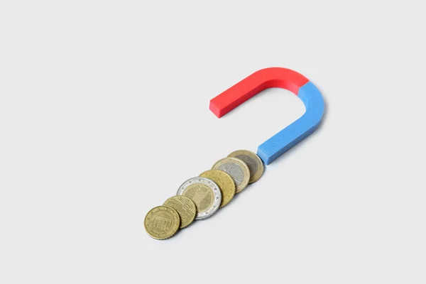 Magnet with coins on white background. Attracting investments concept