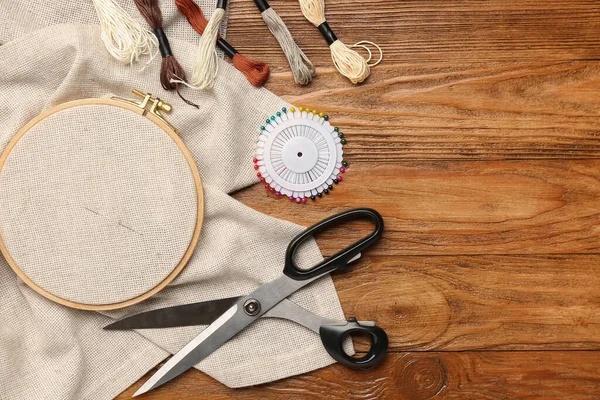 用帆布 毛线线和剪子在褐色木制背景上织成的绣花圈 — 图库照片