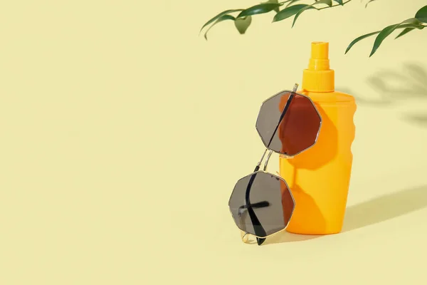 Пляшка Сонцезахисного Крему Сонцезахисними Окулярами Гілкою Дерева Блідо Жовтому Фоні — стокове фото
