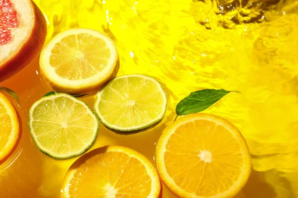 Diferentes Fatias Frutas Cítricas Folhas Água Fundo Amarelo — Fotografia de Stock