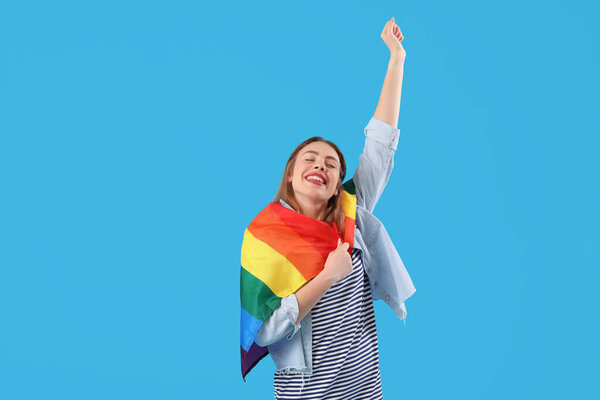 Счастливая молодая женщина с флагом ЛГБТ на синем фоне