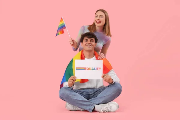 ピンクの背景に単語EqualityとLgbtの旗を持つ若いカップル — ストック写真