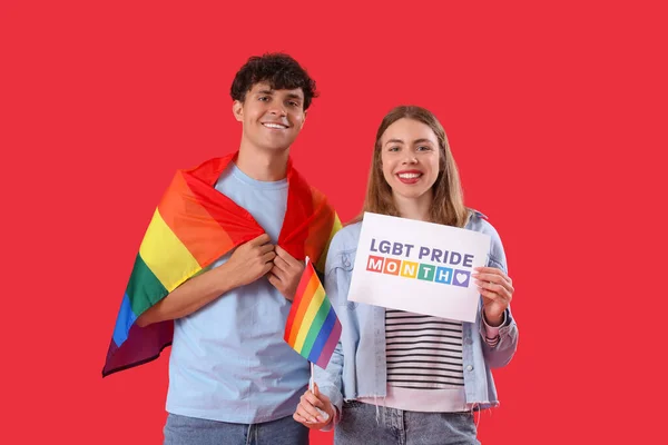 Lgbtの旗を持つ若いカップルと赤い背景にプライド月間のカード — ストック写真