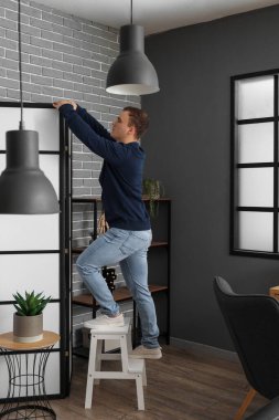 Merdivendeki genç adam, odada katlanan perdenin yanında.