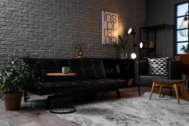 Oturma odasının içinde siyah kanepe ve akşamları parlayan lambalar