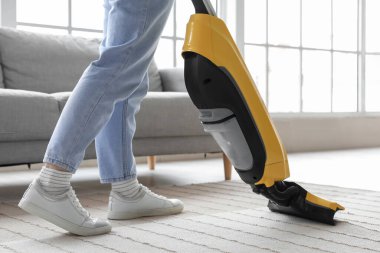 Evde süpürge yapan genç bir kadın, yakın plan.