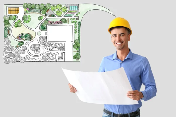 Male landscape designer with drawing on grey background