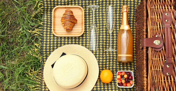 stock image Wicker basket with hat, tasty food and drink for romantic picnic in park