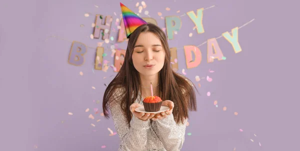 Mujer Joven Soplando Vela Pastel Cumpleaños Contra Fondo Lila —  Fotos de Stock
