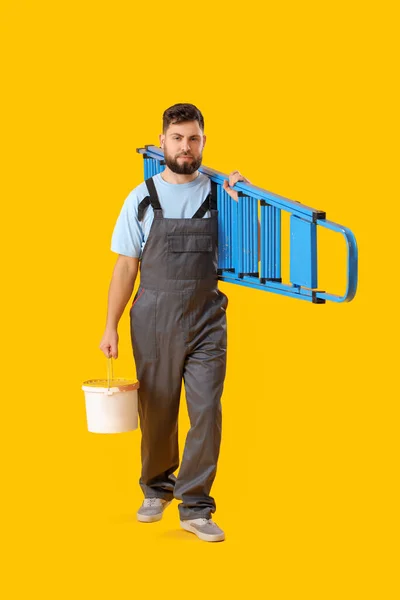 Mannelijke Arbeider Met Ladder Blik Verf Gele Achtergrond — Stockfoto