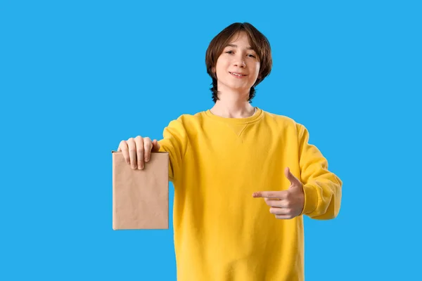 Genç Çocuk Mavi Arka Plan Kitabını Işaret Ediyor — Stok fotoğraf
