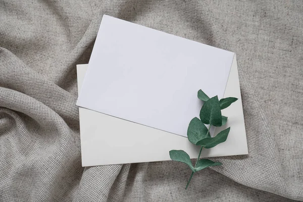 空の招待カードとともにユーカリの枝上灰色のしわテーブルクロス — ストック写真