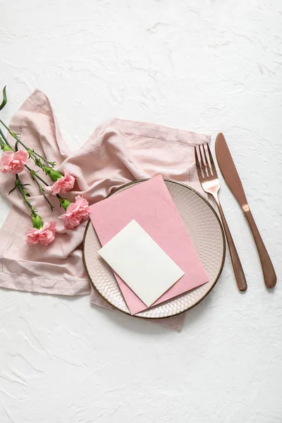白いテーブルの上に空白の招待状カード カトラリー カーネーションの花できれいなプレート — ストック写真