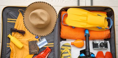 Plaj aksesuarları, pasaport ve fotoğraf makinesi olan bavulu aç.