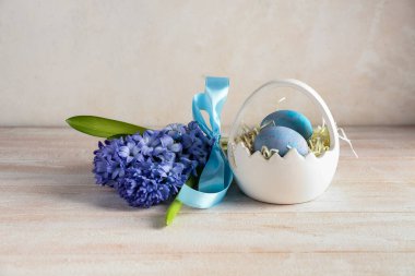 Güzel sümbül çiçekleri ve sepet, bej duvarın yanındaki masada Paskalya yumurtaları.