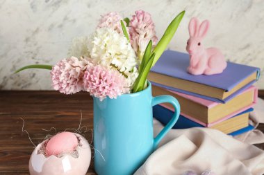 Güzel sümbül çiçekli vazo, tavşancık ve bej duvarın yanındaki tahta masada Paskalya yumurtası.