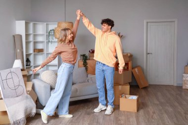 Genç çift taşınma gününde odada dans ediyor.