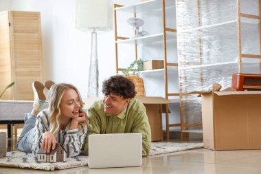 Taşınırken yatak odasında dizüstü bilgisayar kullanan genç bir çift.