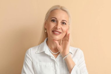 Mature blonde woman on beige background, closeup