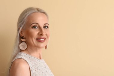Mature blonde woman on beige background, closeup