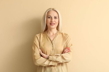 Mature blonde woman on beige background